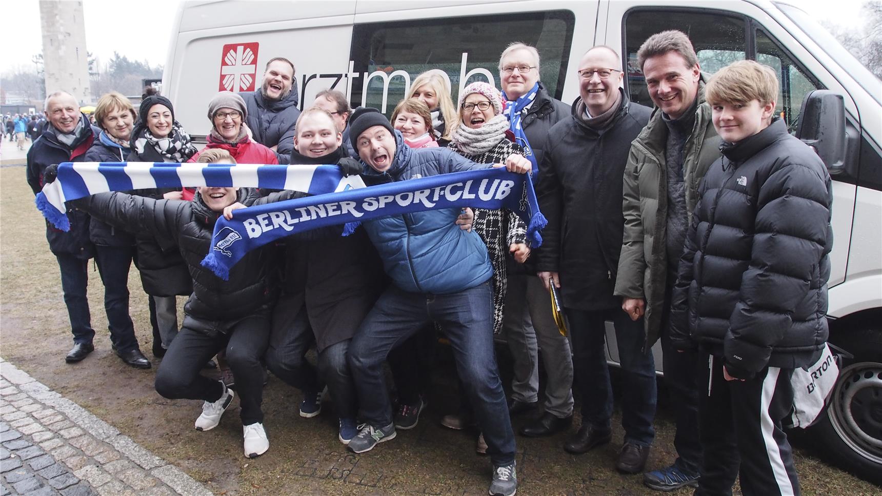 Caritas-Mitarbeiter und Hertha-Fans vor dem Arztmobil