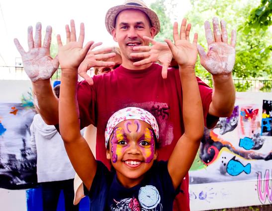 Ein kleines Mädchen und ein Mann Strecken ihre bemalten Handflächen in die Kamera