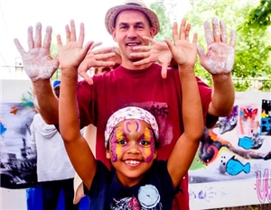Ein kleines Mädchen und ein Mann Strecken ihre bemalten Handflächen in die Kamera