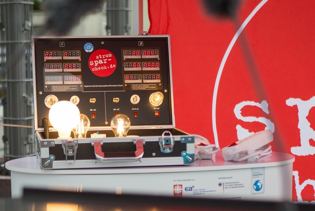 Der Koffer des Projekts Stromspar-Check mit leuchtender Glühbirne 