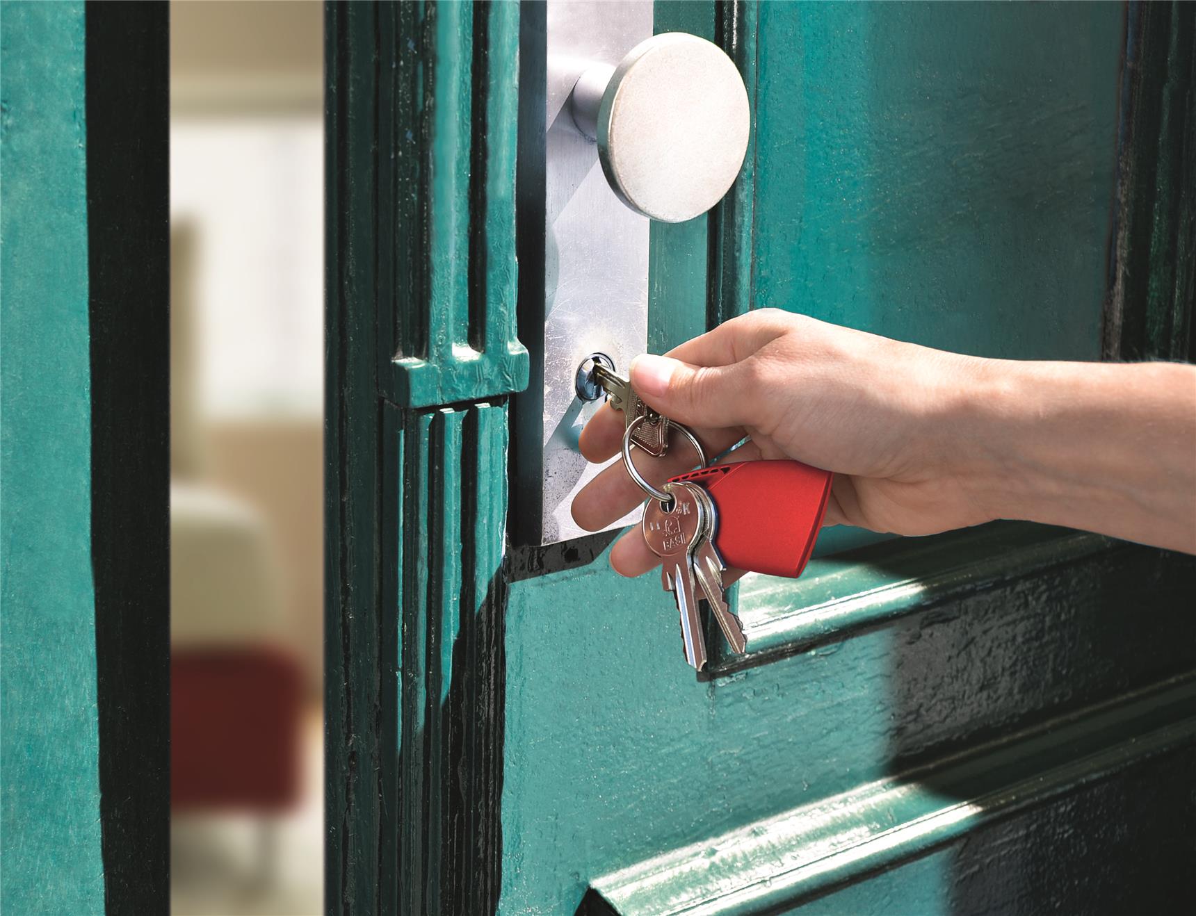 Eine Hand die mit einem Schlüssel gerade eine Tür öffnet