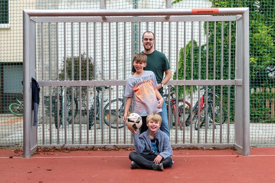 Zwei Jungs spielen mit einem Mann Fußball