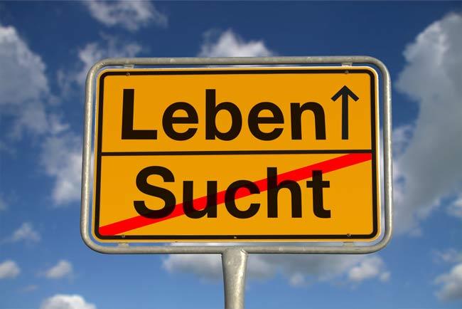 Ein gelbes Ortsschild zeigt ein rot durchgestrichenes Wort 