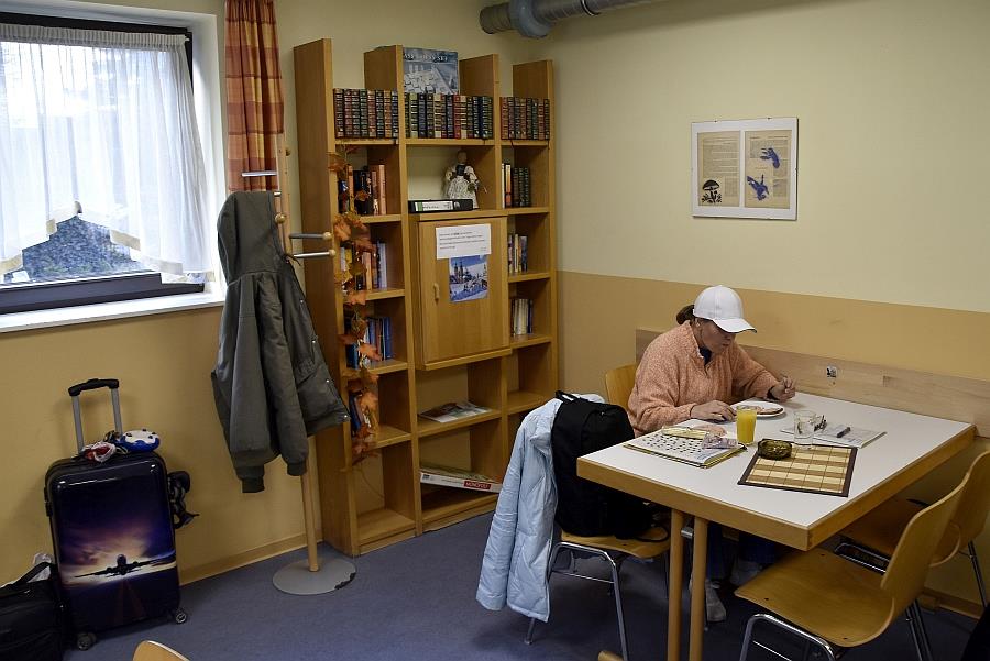 Eine Frau sitzt einsam in einem hellen Zimmer.