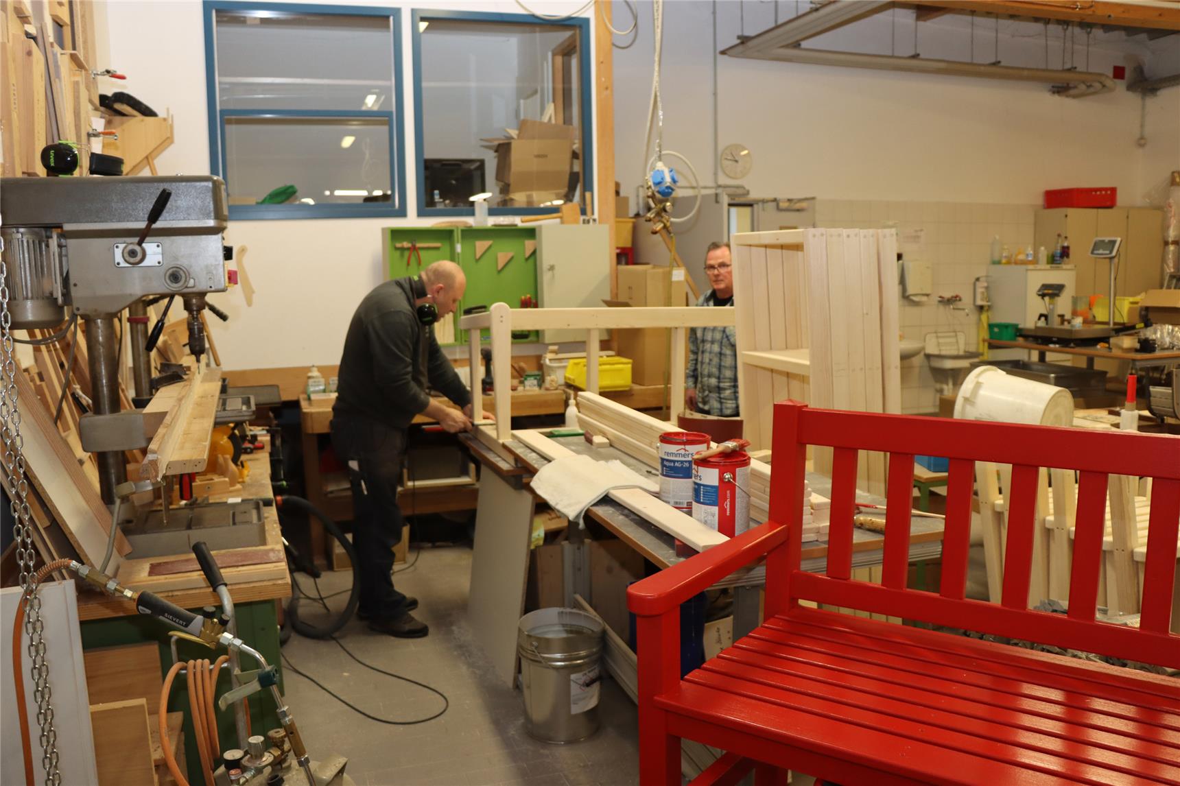 Wir sehen in einer Schreinerwerkstatt eine große rotee Sitzbank.