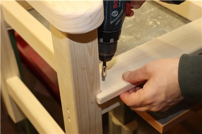 In einer Ecke der Bank wird eine Schraube eingefügt.