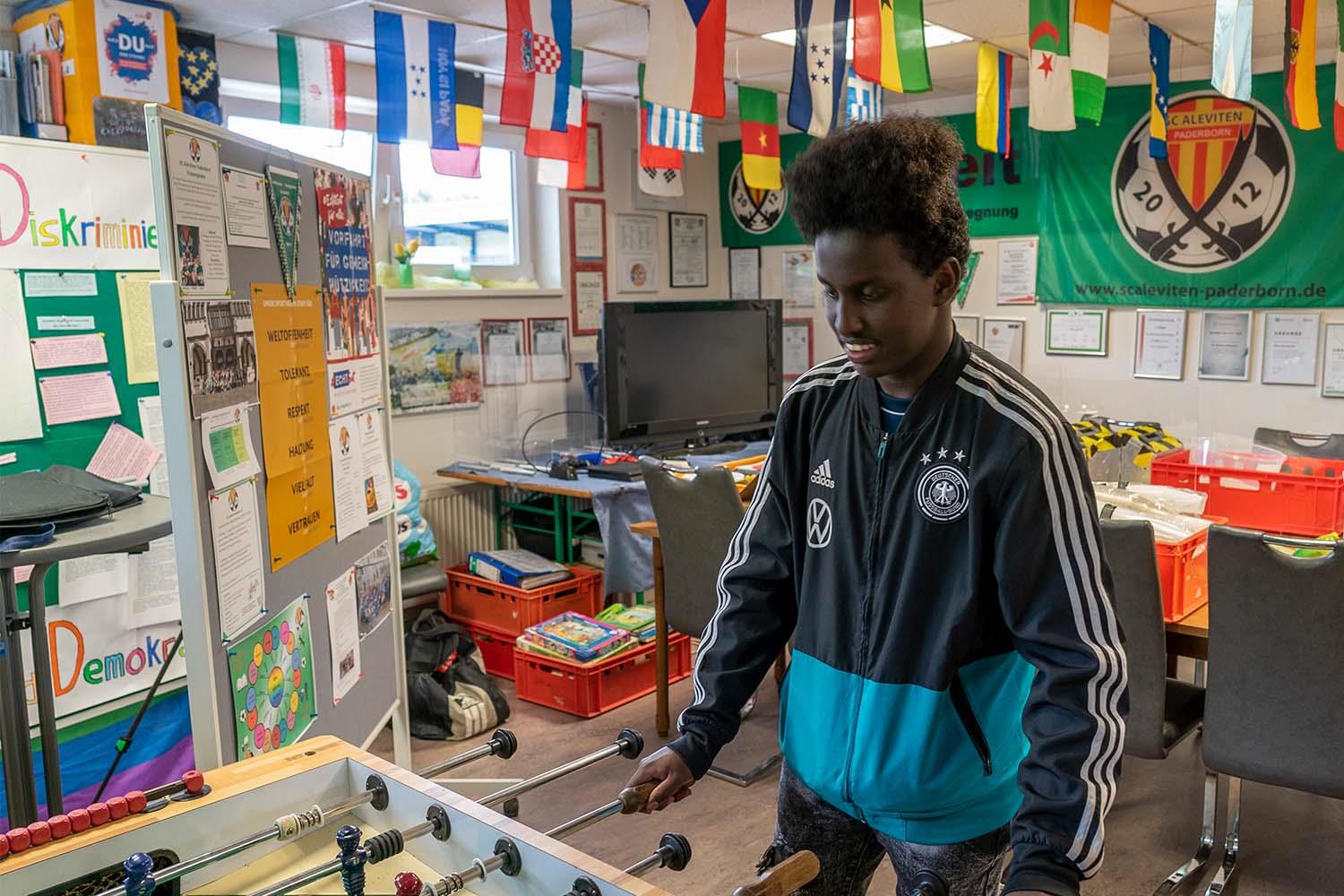 Ein junger Mensch spielt Tischfußball und lacht.