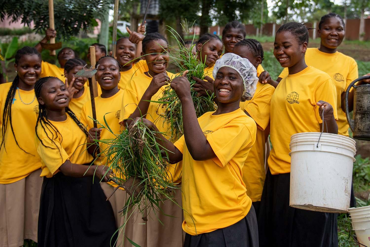 Mehrere junge Frauen mit gelben Pullover haben Werkzeuge in Hand und lachen.